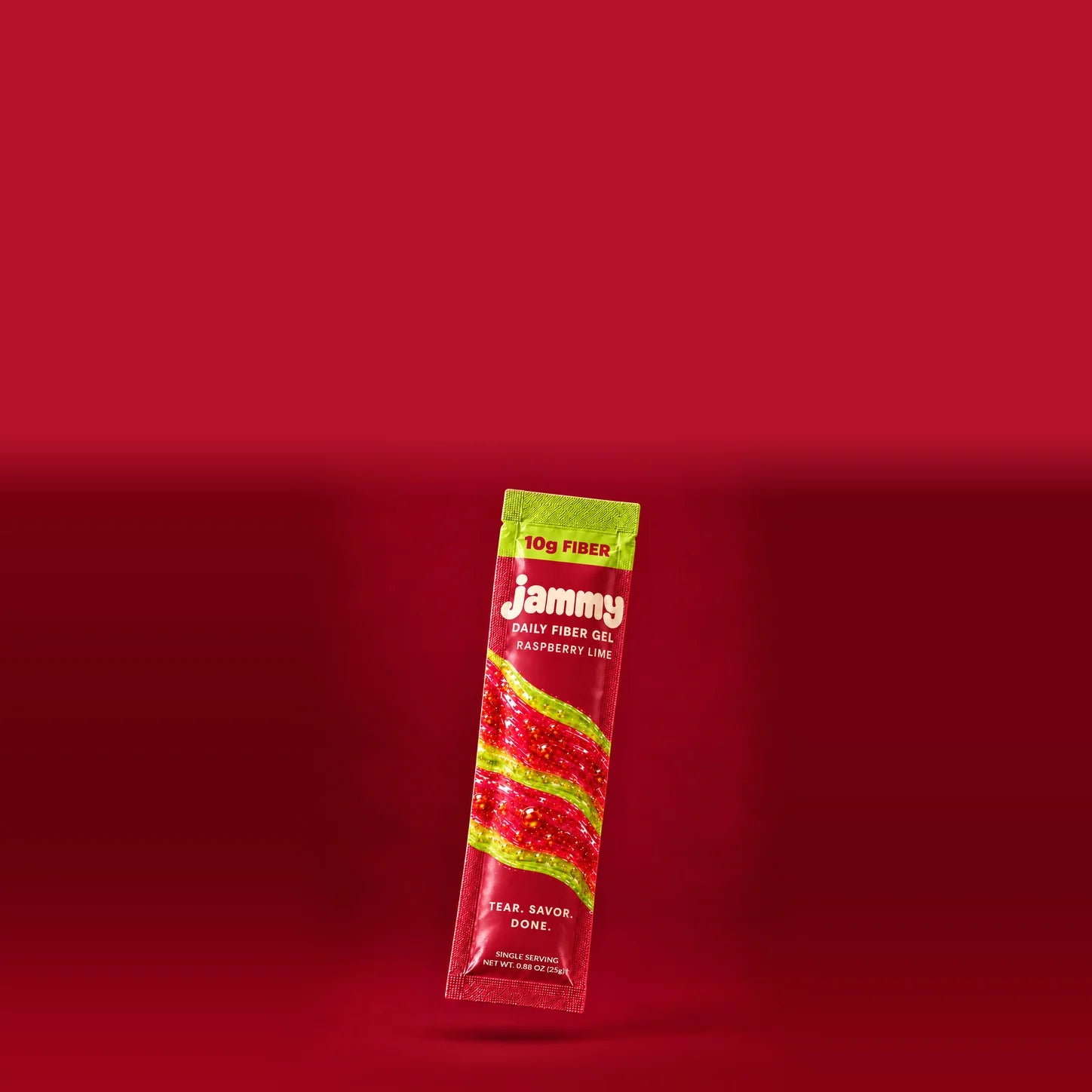 A red Jammy raspberry lime gel stick with a cream logo and solid lime-green top and seal framing the 10g fiber text, suspended against a berry-red studio background